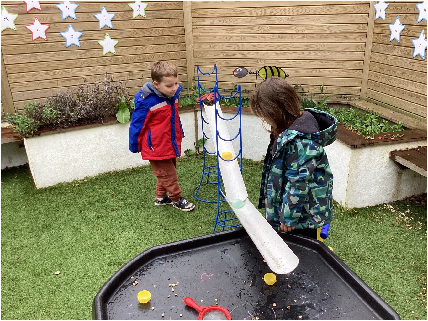 Young children exploring water play equipment at Little Acorns